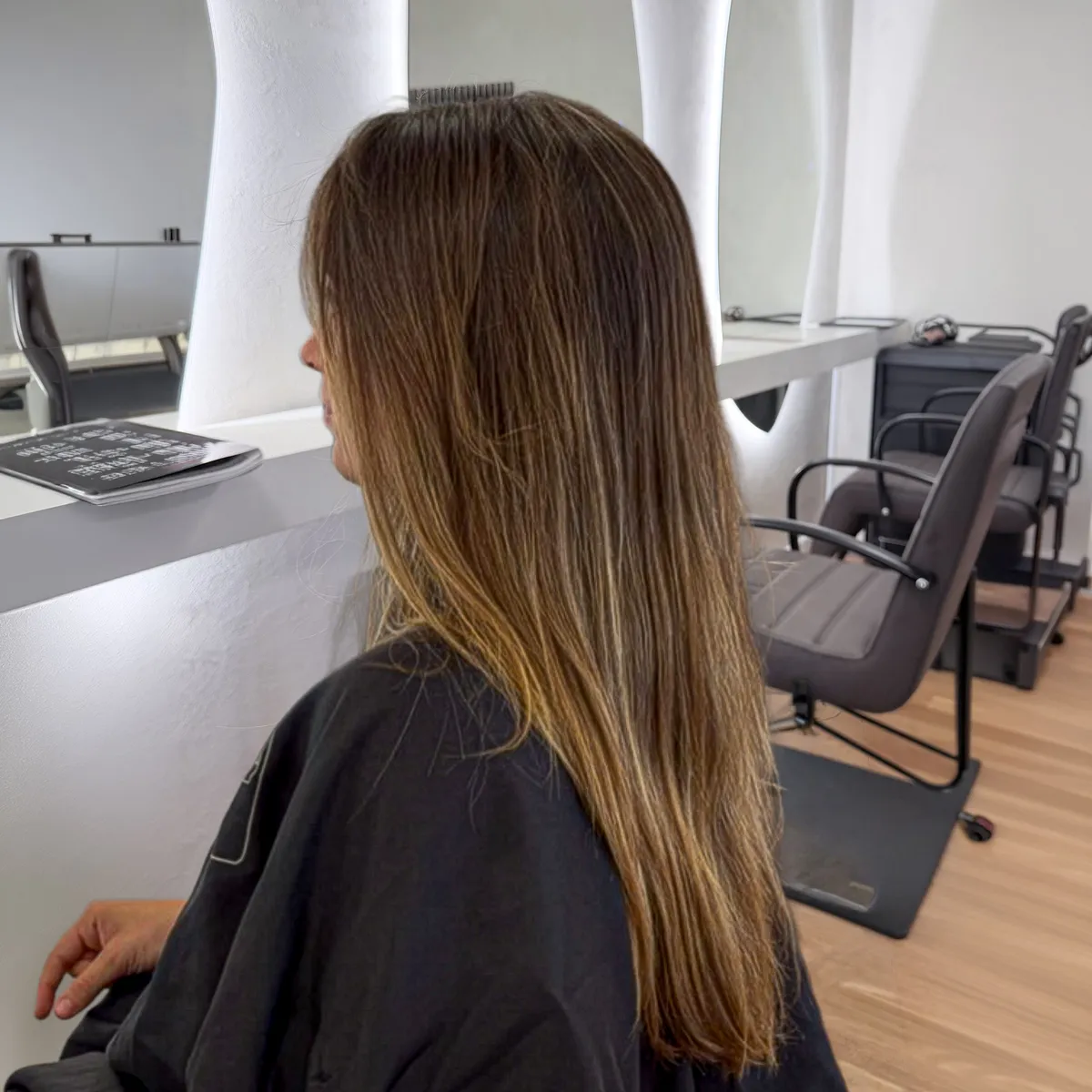 Long brunette-to-blonde balayage with a soft, dark root melting into creamy blonde waves — before