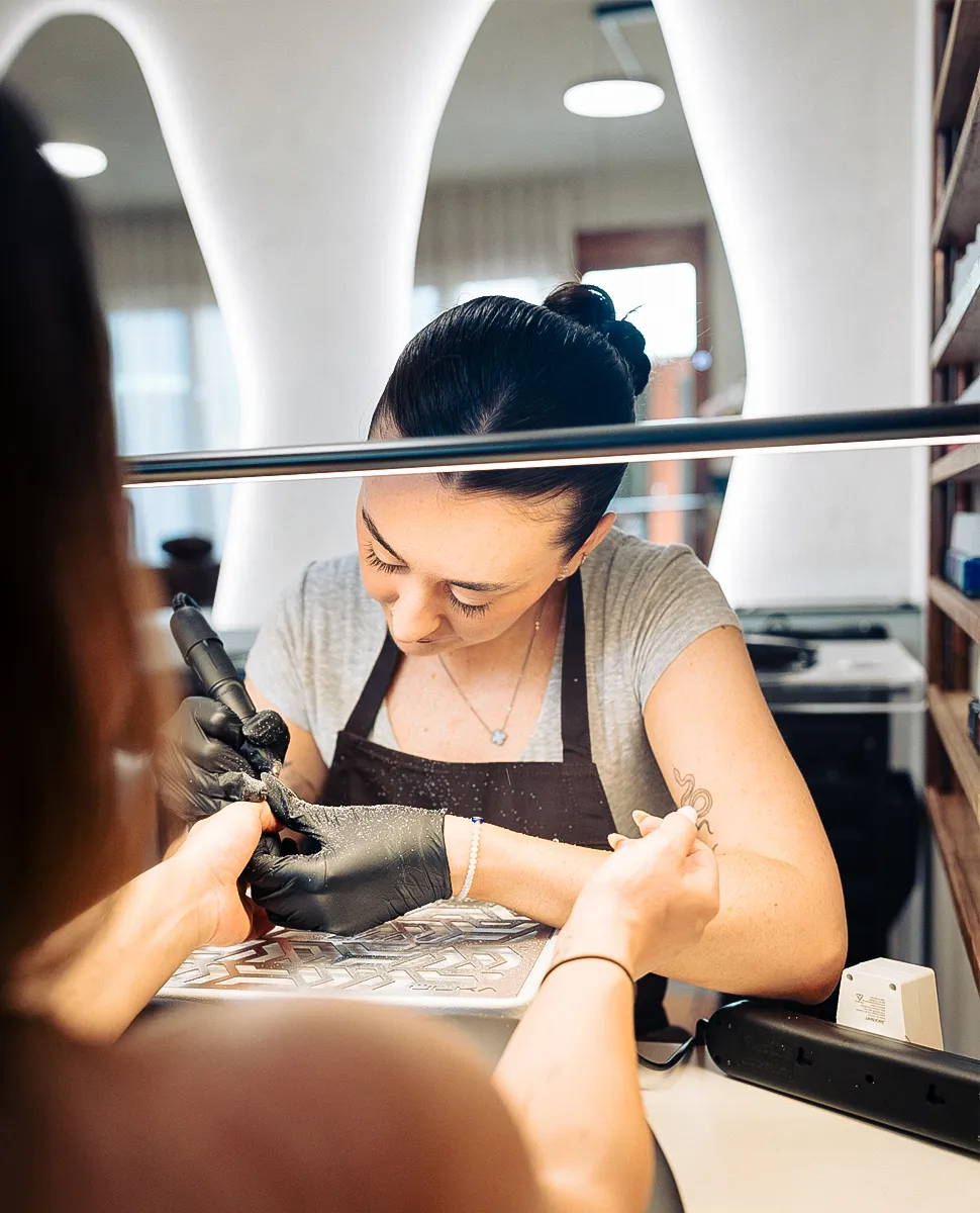 Nail technician using an e-file on a client's nails at Olaya & Co. in Byron Bay