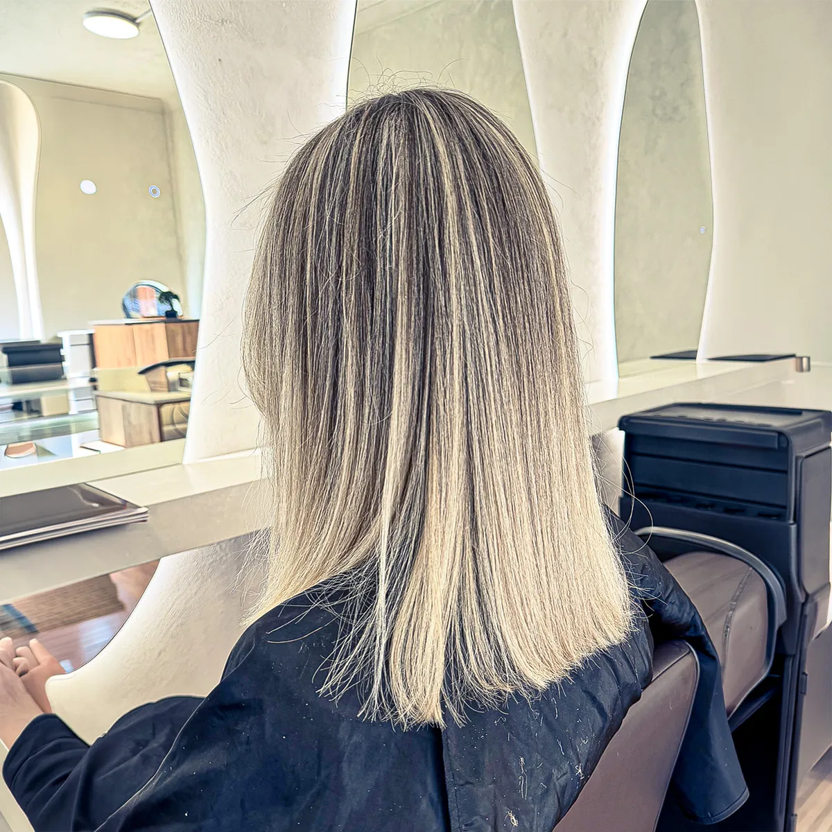 Shoulder-length bright blonde highlights with a soft shadow root, styled sleek and straight — after