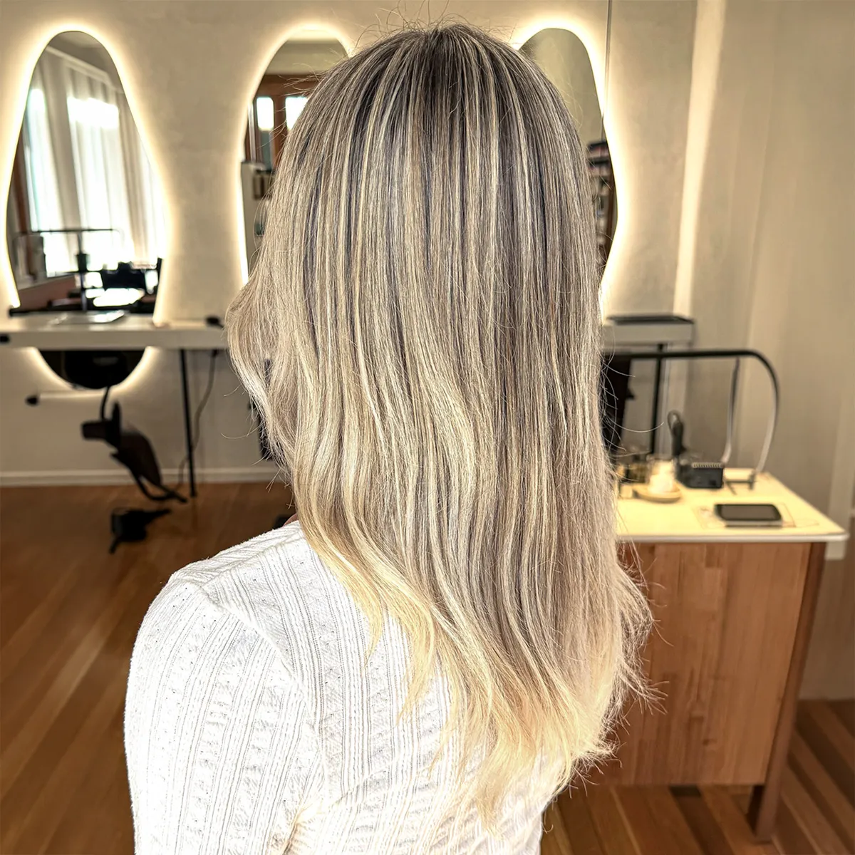 Long, bright blonde balayage with a soft shadow root, blended through loose waves — after