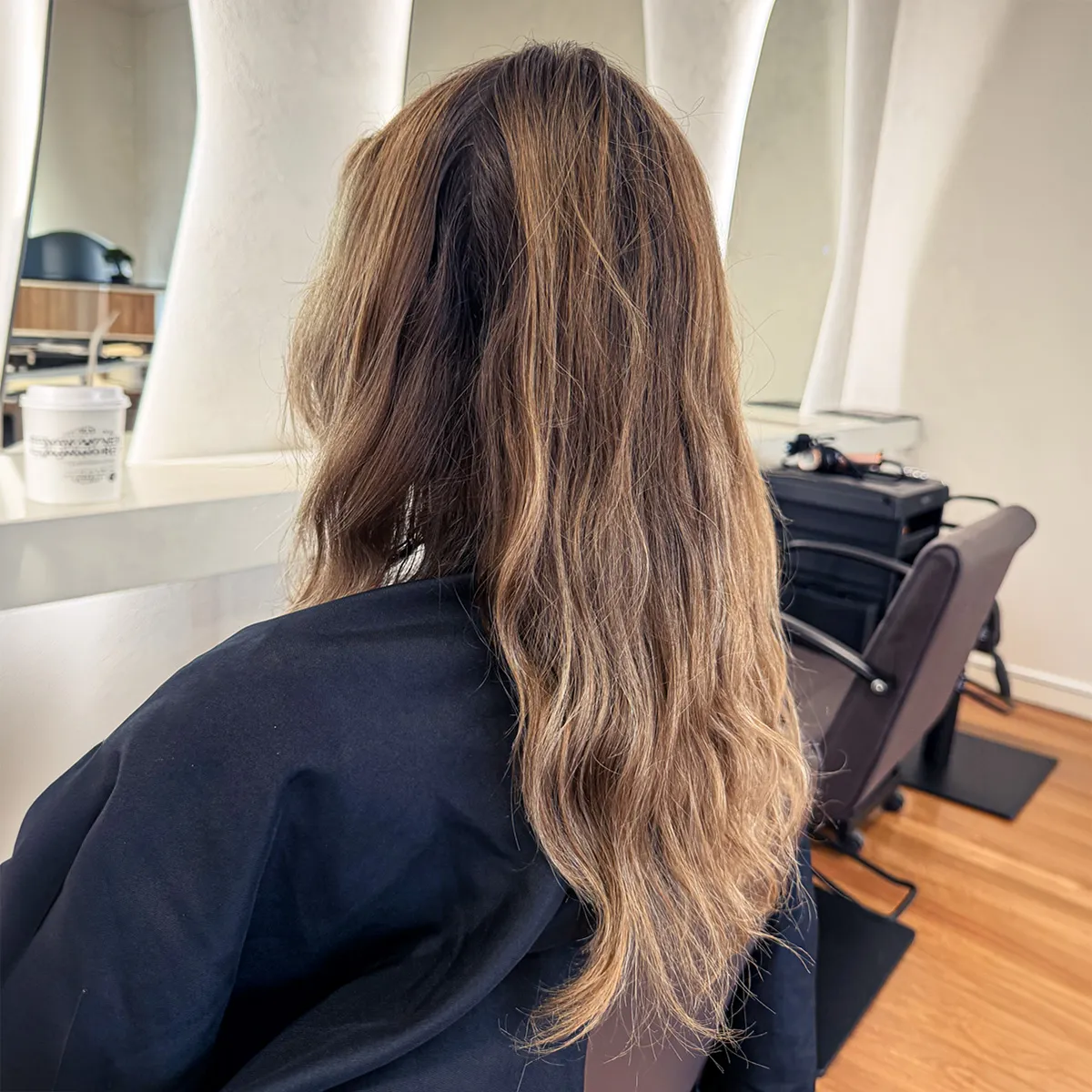 Long, bright blonde balayage with a soft shadow root, blended through loose waves — before