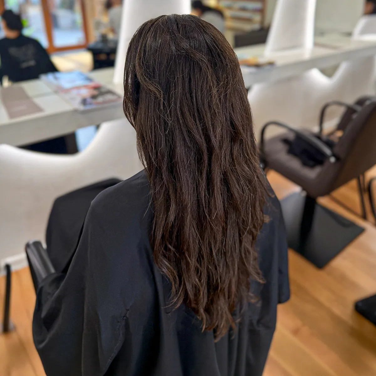 Long brunette melt with soft caramel ribbons blended through voluminous loose curls — before