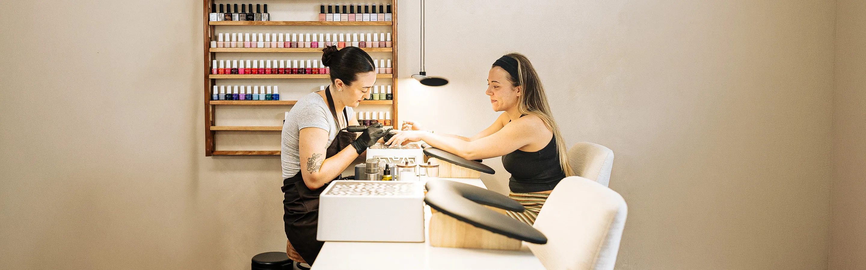 Nail technician giving a smiling client a manicure in the salon