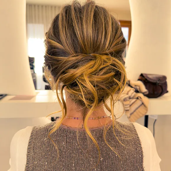 Back view of a loose, textured low bun with soft blonde highlights