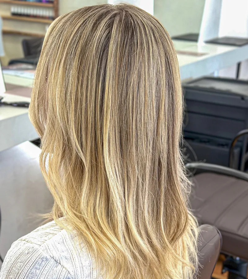Client with smooth, glossy blonde balayage waves