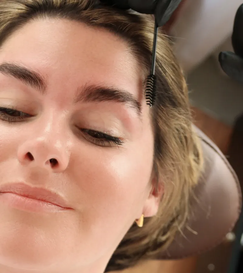 Close-up of brows coated in lamination lotion and brushed upward during treatment