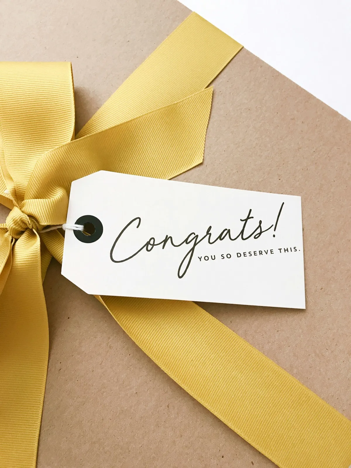 A wrapped gift with a gold ribbon and a gift tag that reads Congrats, you so deserve this