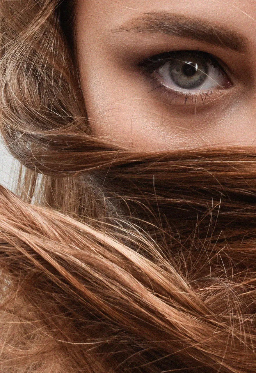 Woman with long, glossy brown hair swept across her face