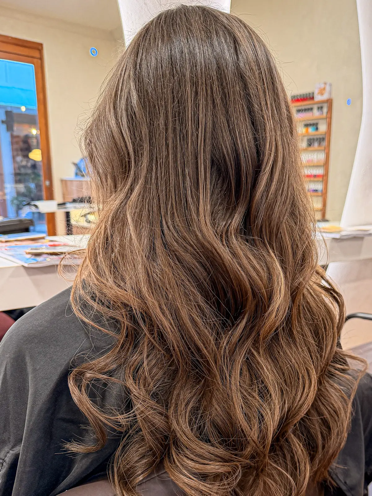 Long brunette hair with soft caramel balayage styled in loose waves