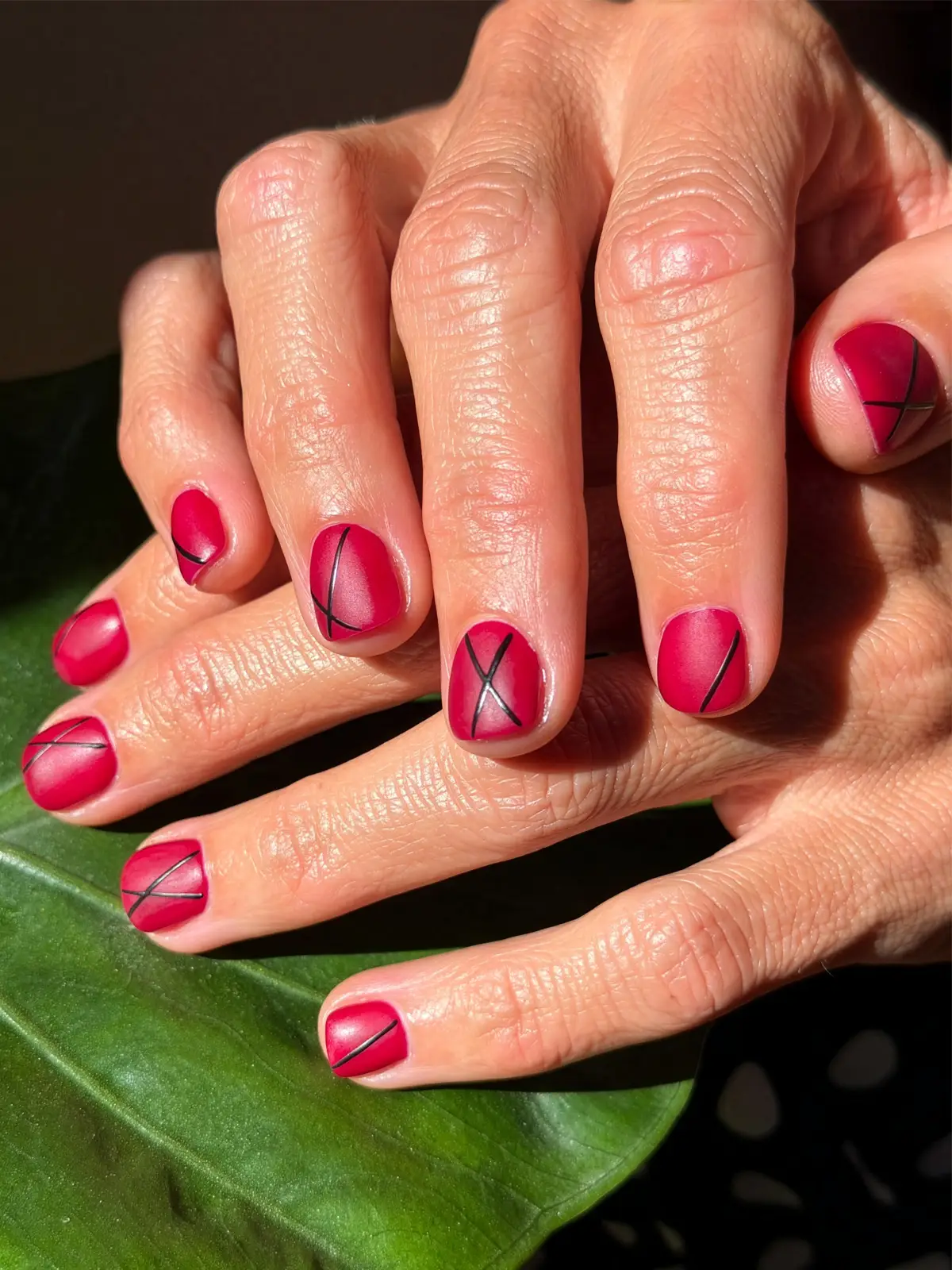 Short matte raspberry nails with fine black criss-cross line art