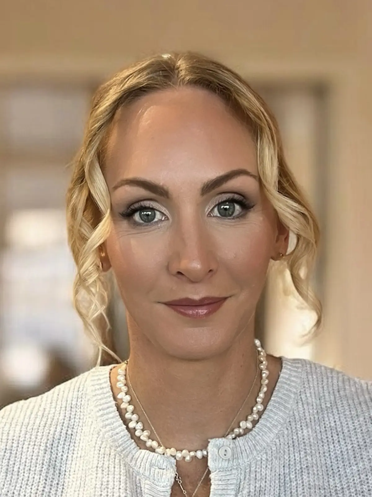 Soft smoky eye with defined brows and a mauve-nude lip, worn with a loose curled updo