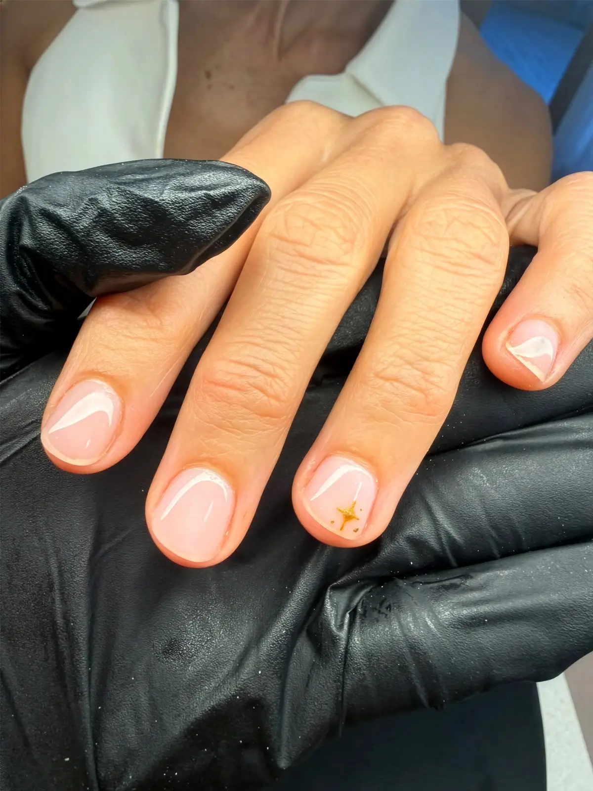 Short nude nails with micro white French tips and a gold star accent