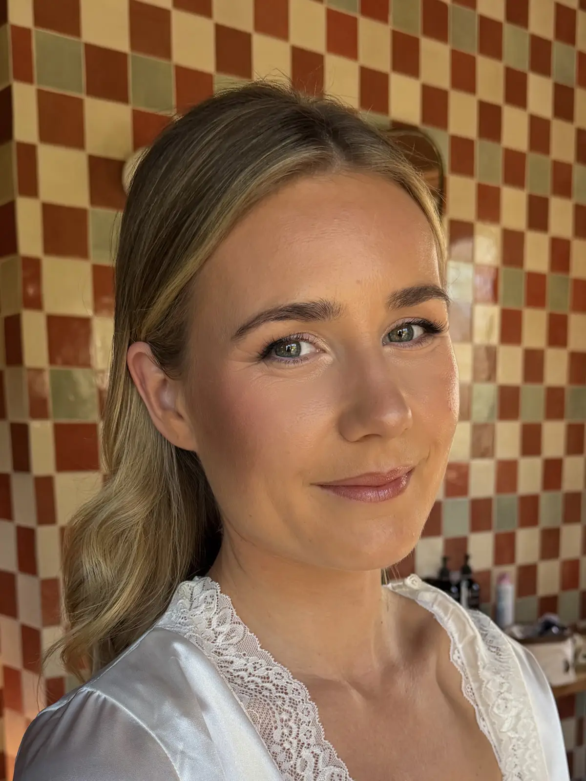 Natural glowing makeup with a soft flush and rosy lip, hair in soft waves