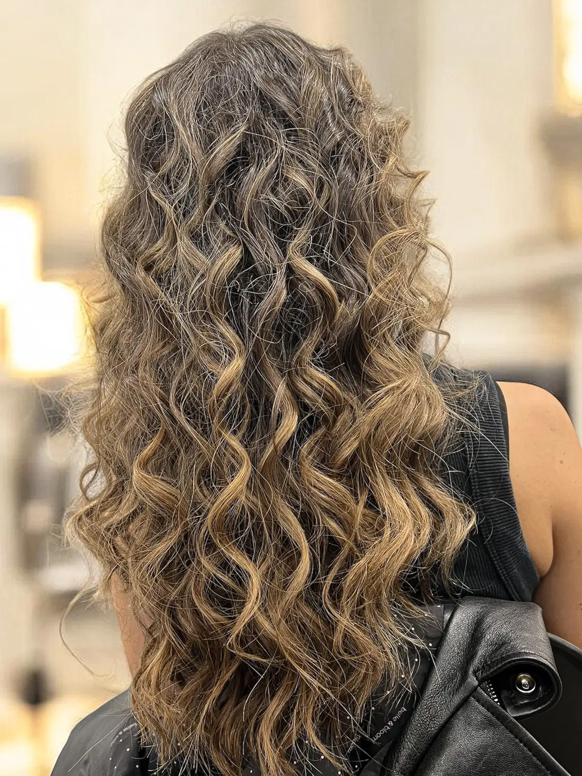 Long curly hair with honey-blonde balayage through the curls