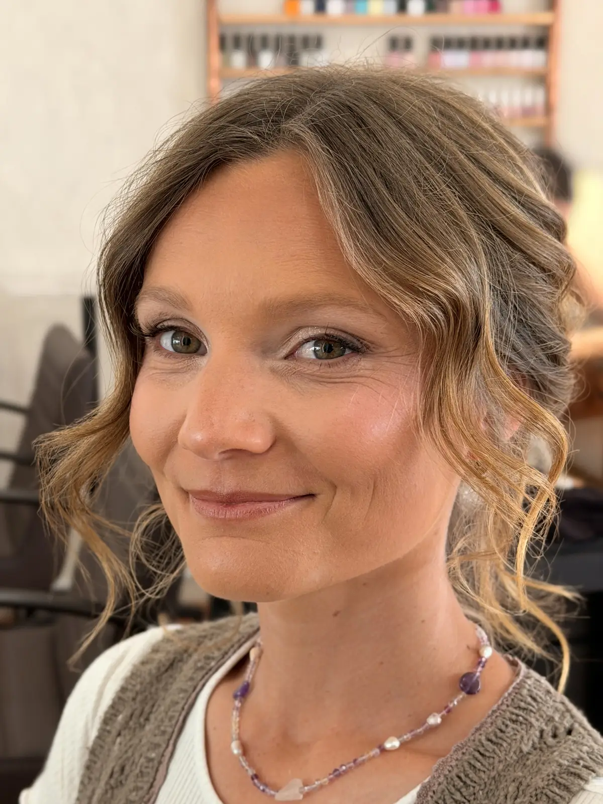 Dewy natural makeup with peachy cheeks and a nude lip, framed by loose curls