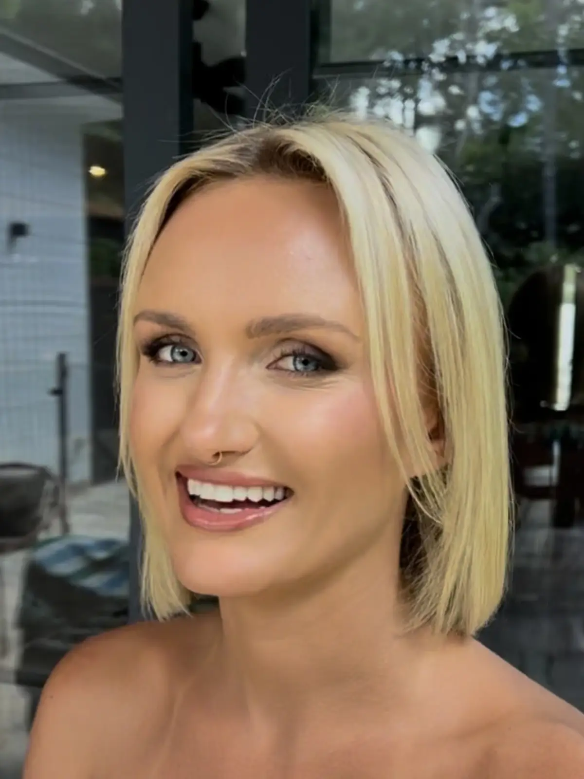 Bronzed glam makeup with smoky liner and a glossy nude lip, sleek blonde bob