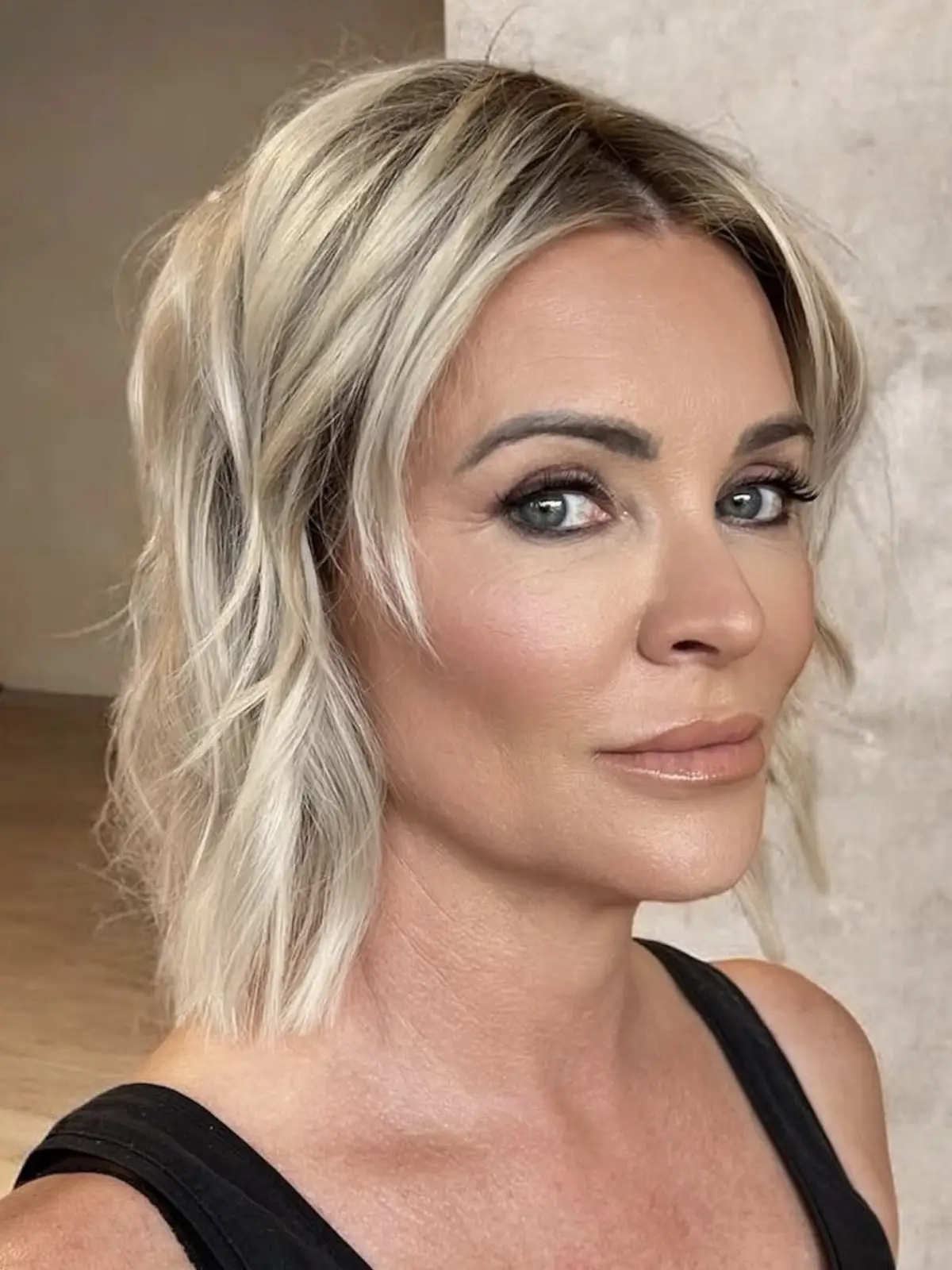 Smoky eye with sculpted cheekbones and a satin nude lip, tousled platinum waves